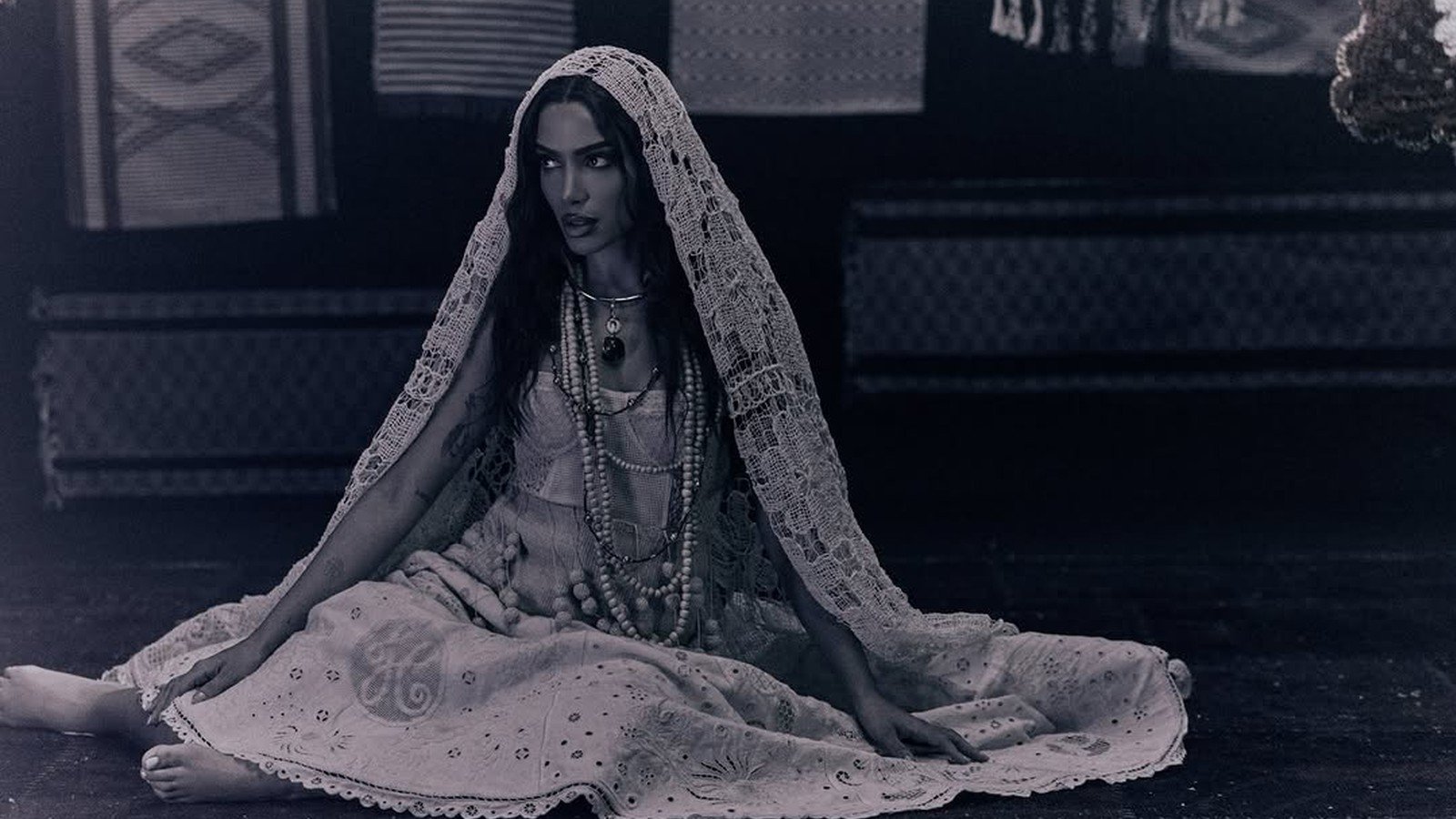 Anitta coberta por um veu branco, sentada, em foto do projeto EQUILIBRIVM