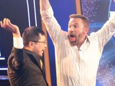 Ben Affleck comemora de braços erguidos no palco do Quem Quer Ser um Milionário