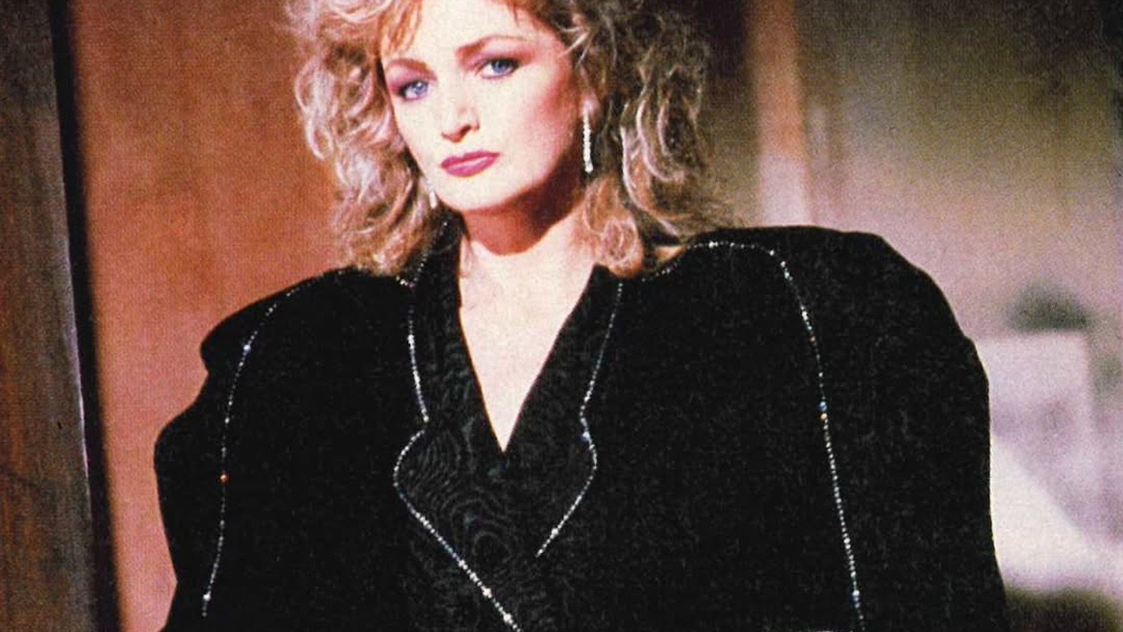 Bonnie Tyler de casaco preto e maos na cintura, em ensaio dos anos 1980