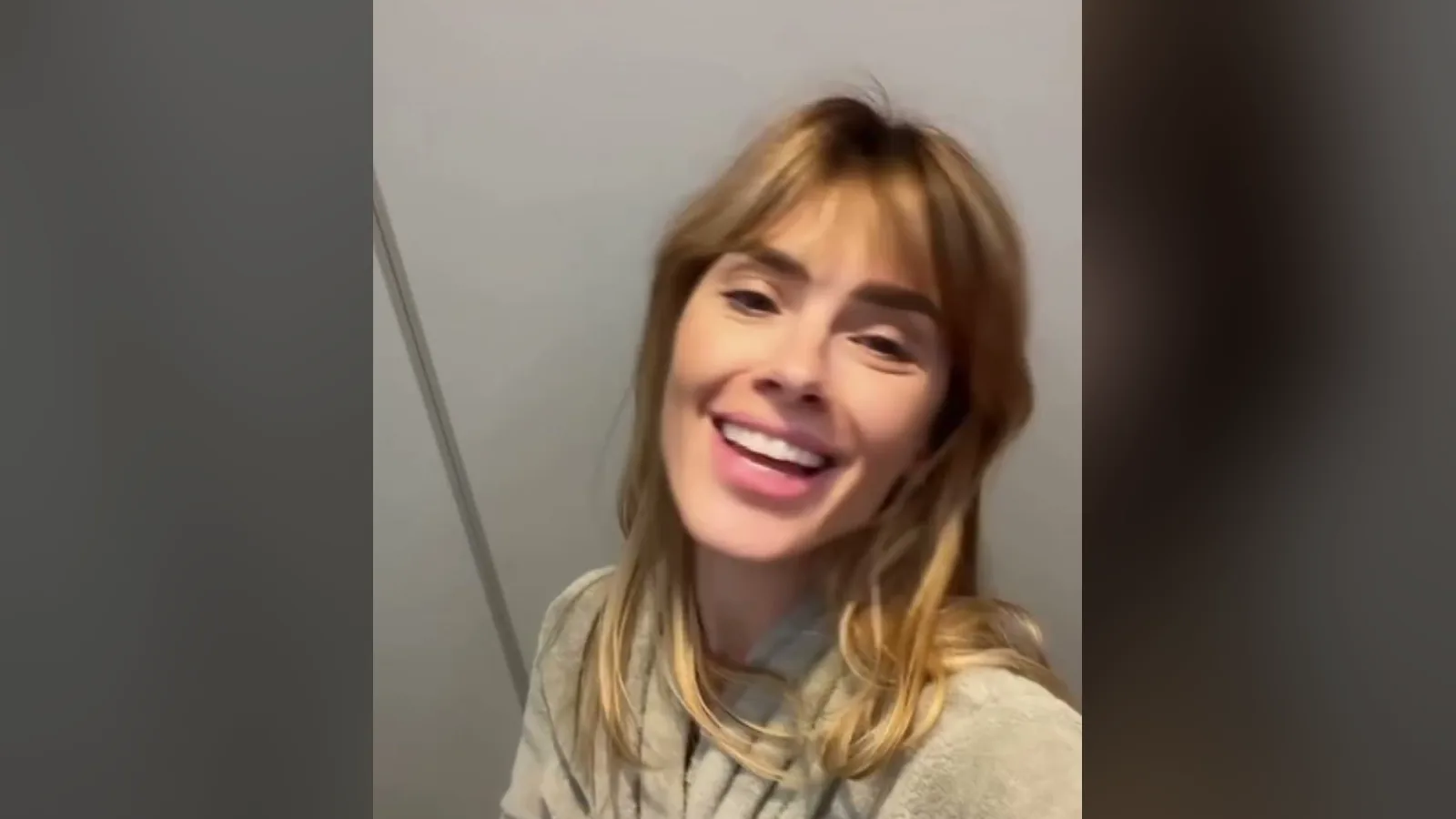 Carolina Dieckmann de roupão, sorrindo para a câmera antes da sessão na clínica