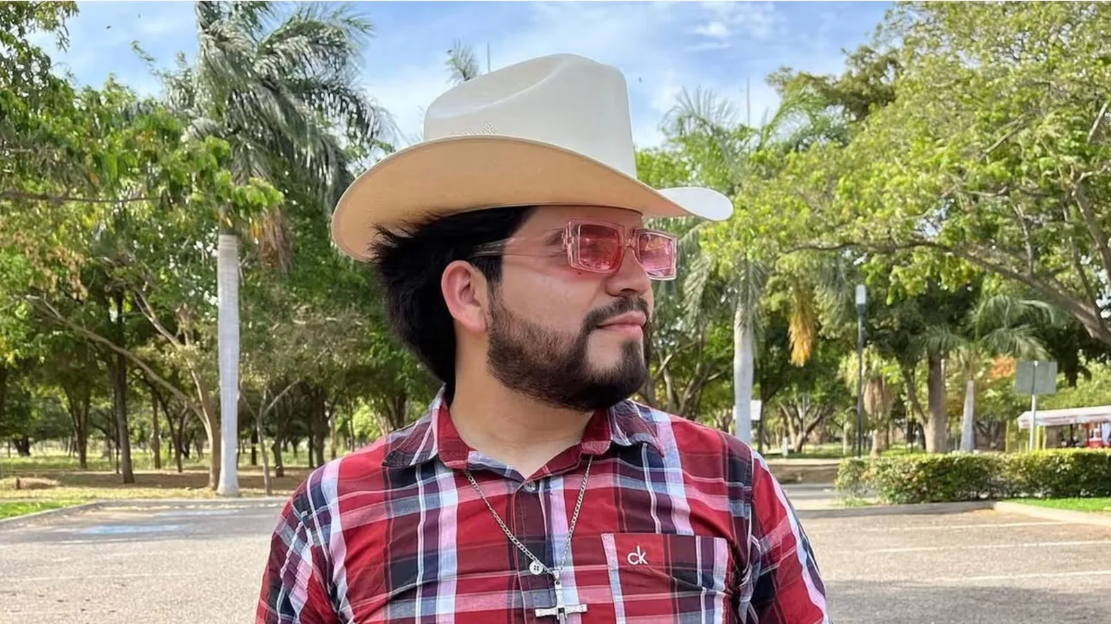 César Gastélum de chapéu de vaqueiro e camisa xadrez, ao ar livre