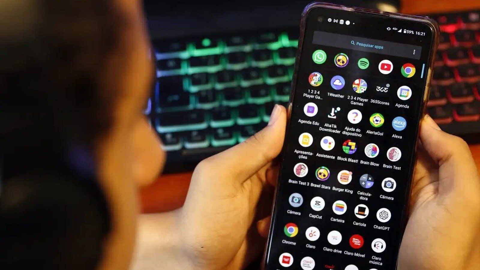 Adolescente de costas segurando celular com a tela de aplicativos aberta