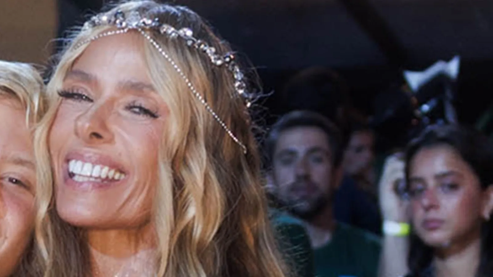 Adriane Galisteu sorrindo, de tiara prateada, em evento noturno