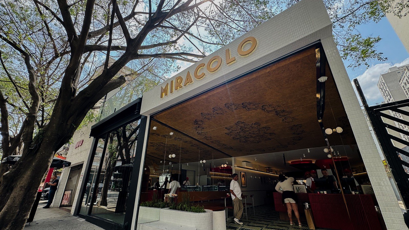 Vista em angulo da fachada da Gelateria Miracolo nos Jardins, com arvores na calcada