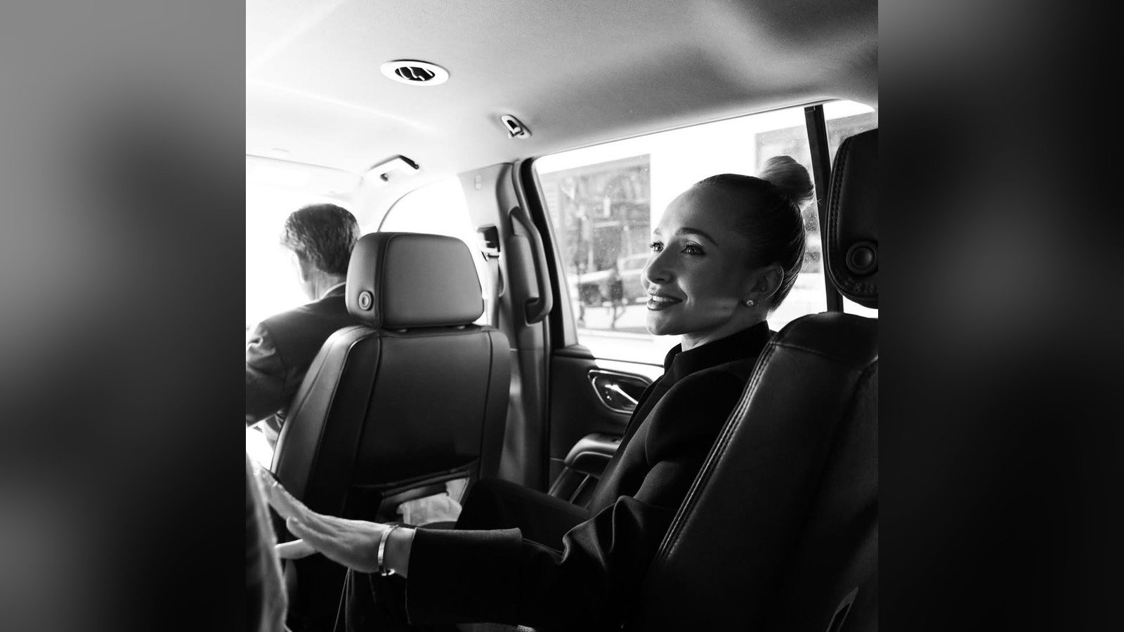 Hayden Panettiere sentada no banco de tras de um carro, em foto preto e branco