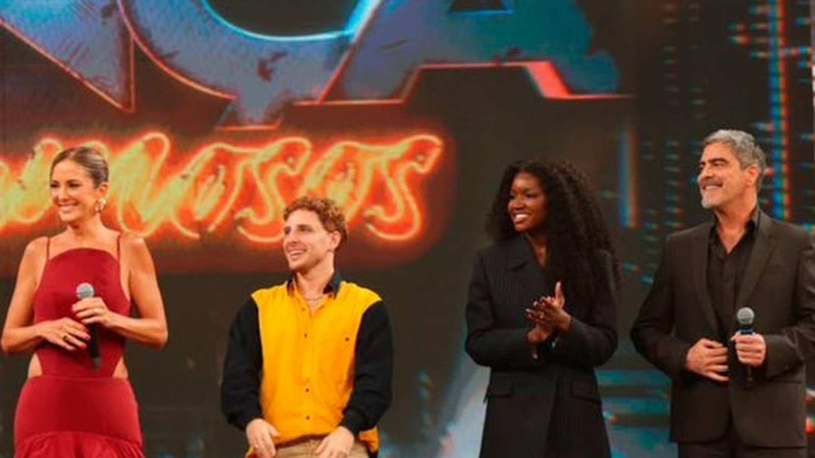 Junno Andrade ao lado de outros participantes no palco do Danca dos Famosos, sob o letreiro do quadro