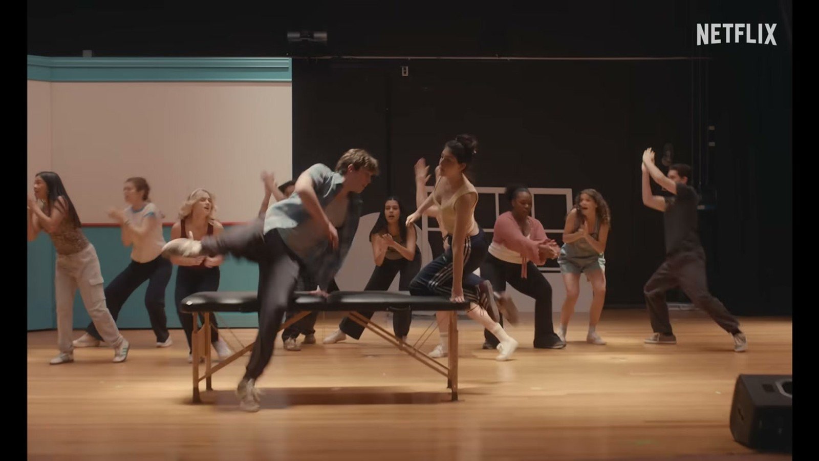 Elenco jovem ensaiando um numero musical no palco da escola