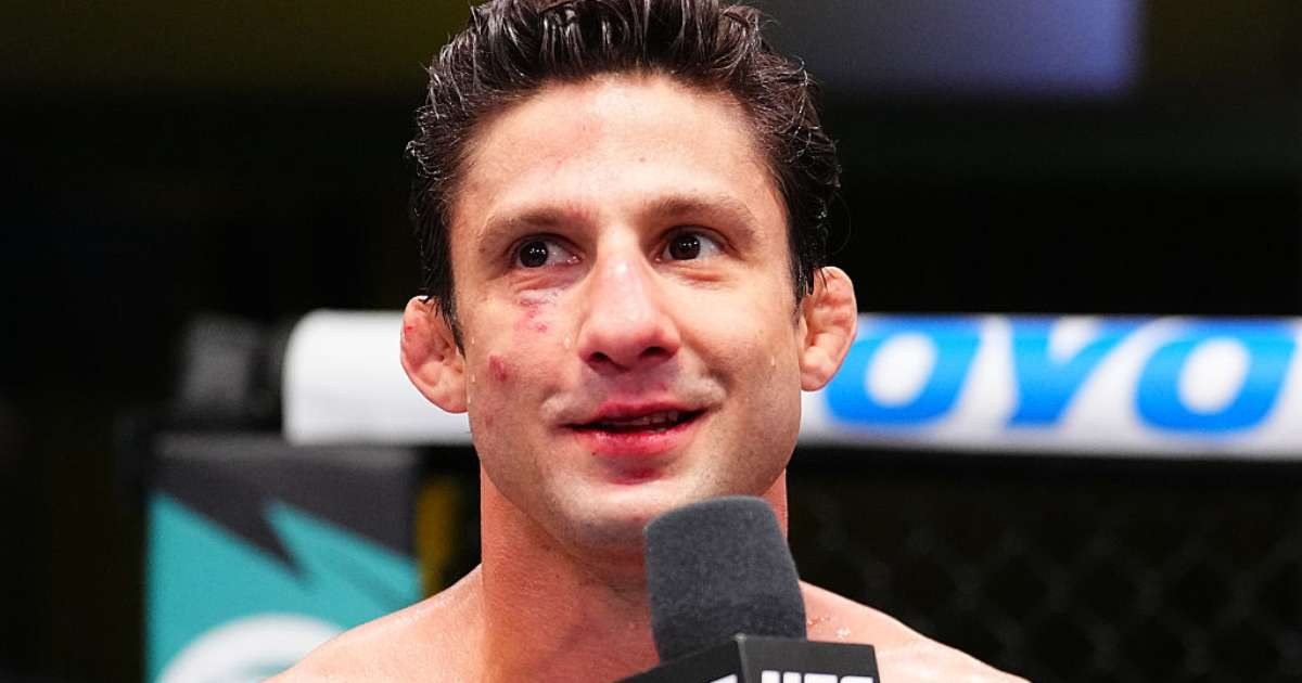 Allan Puro Osso Nascimento dentro do octógono do UFC, com marcas de luta no rosto, falando ao microfone