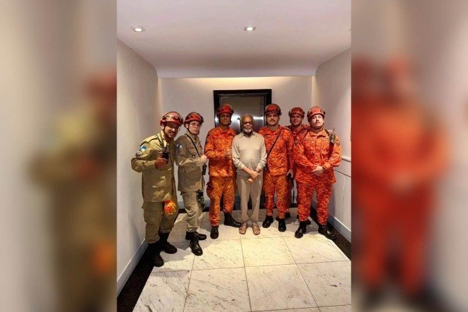 Gilberto Gil ao lado de seis bombeiros militares em frente ao elevador do prédio onde mora, em Copacabana