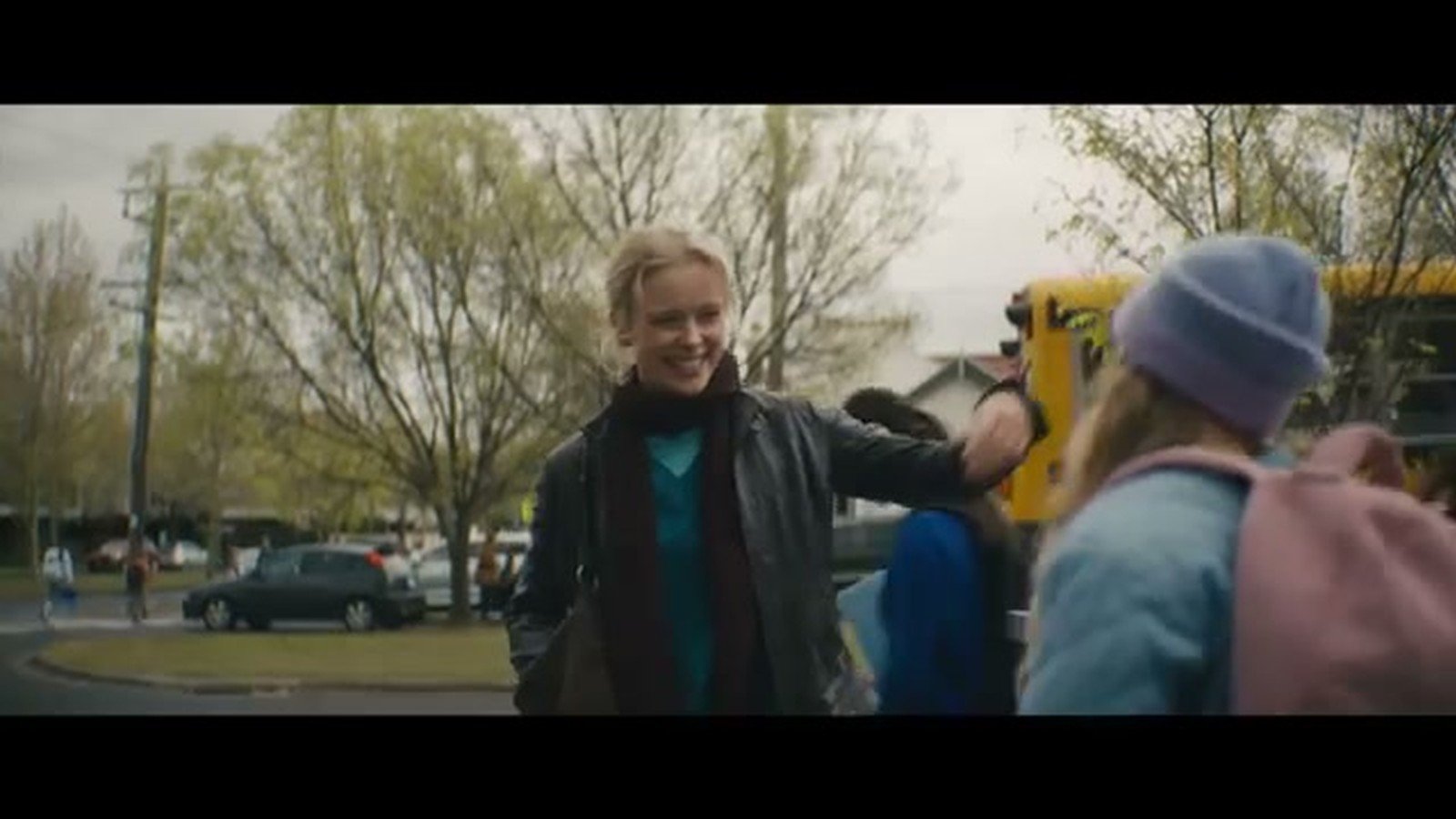 Cena de Sobrenatural Agora Entre Nos: a protagonista Gemma abraca a filha na calcada, com um onibus escolar amarelo ao fundo