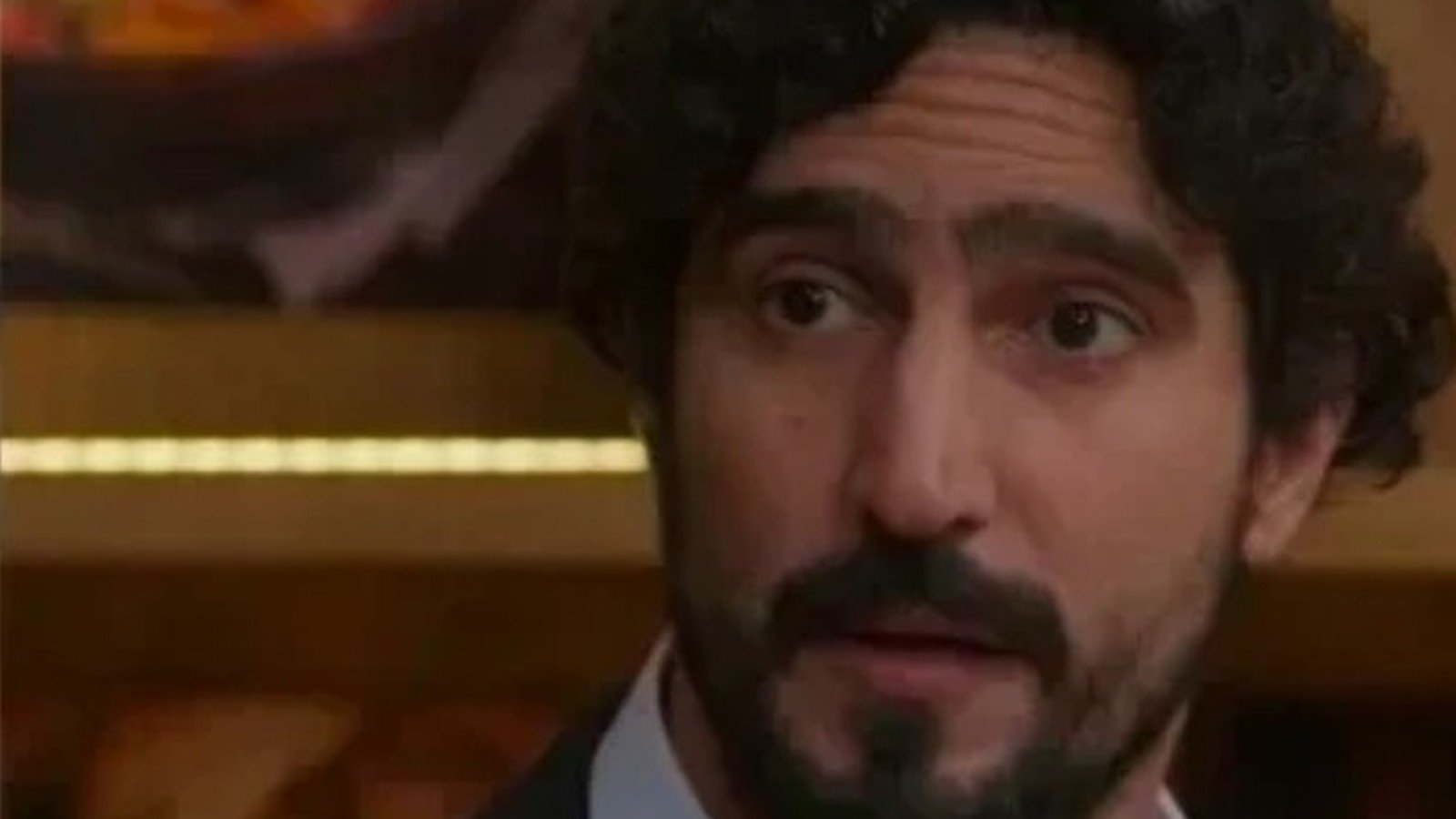 Renato Goes de terno escuro e camisa clara, em cena de novela