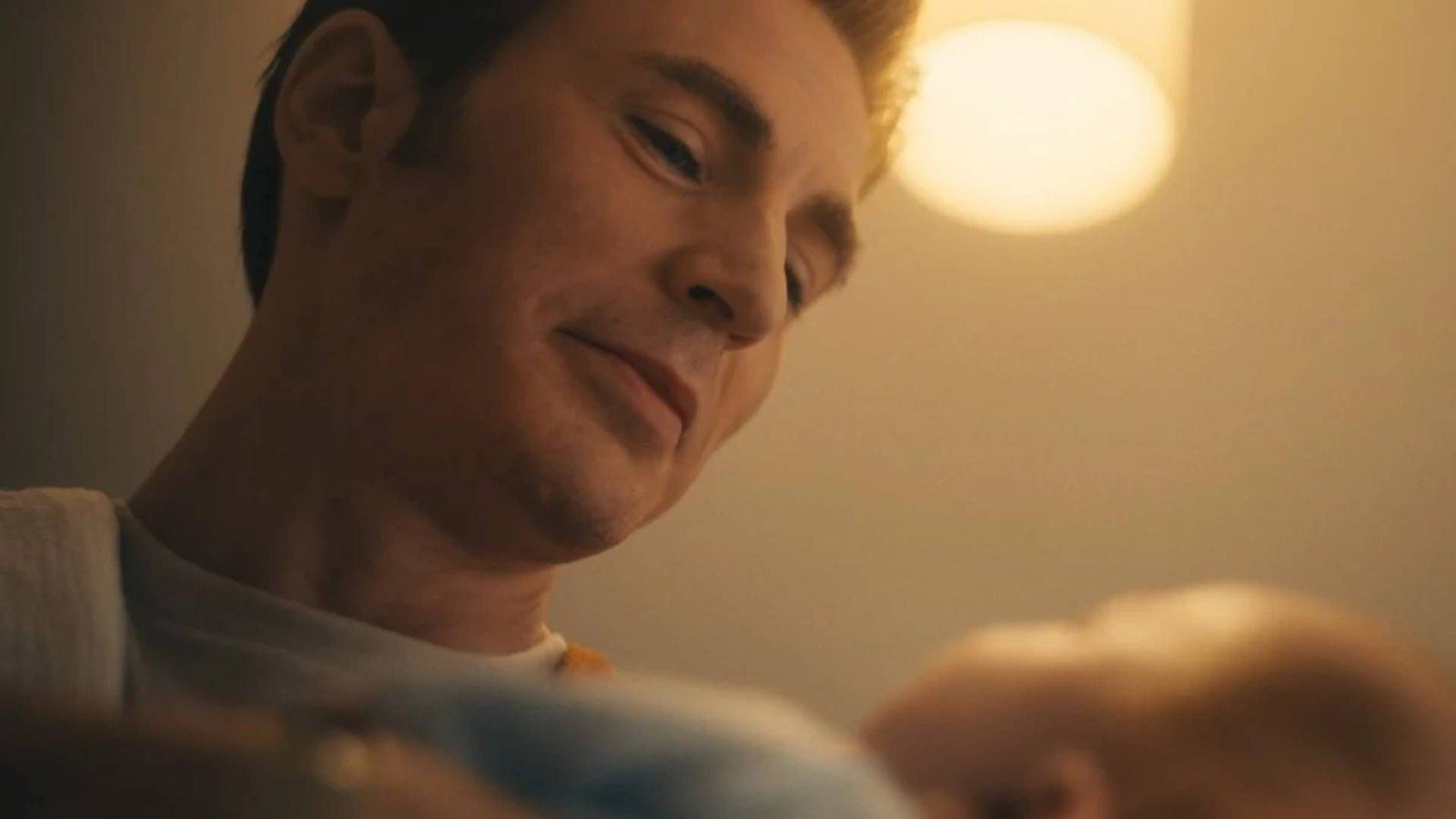 Chris Evans, de camiseta branca, olha para baixo sorrindo em imagem divulgada de Vingadores: Doutor Destino