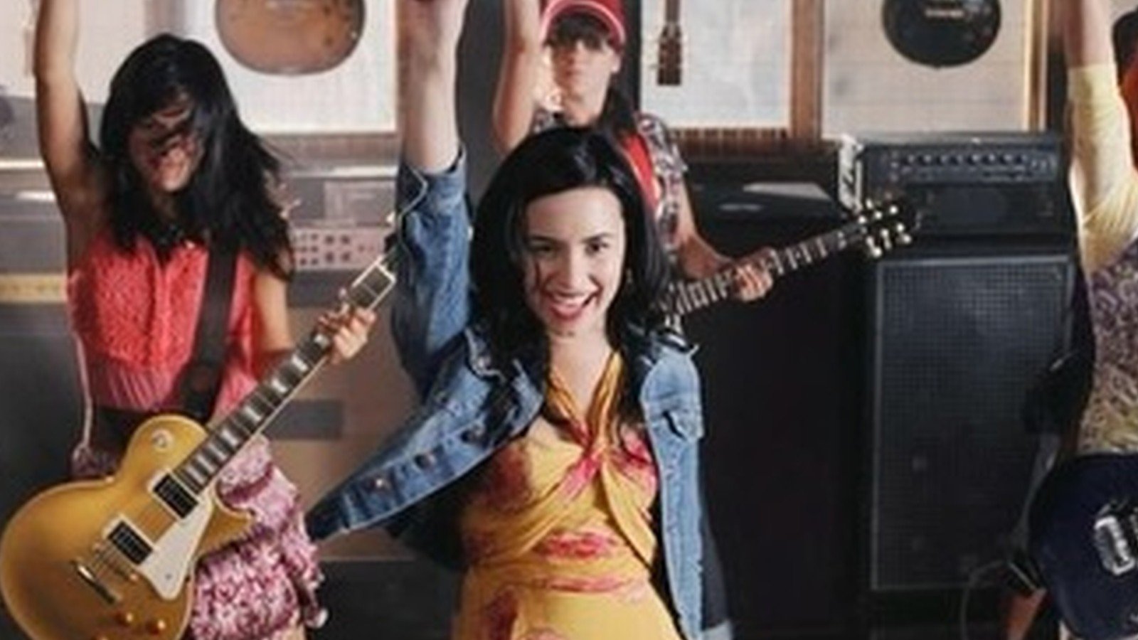 Demi Lovato jovem com guitarra no palco, em cena do primeiro Camp Rock
