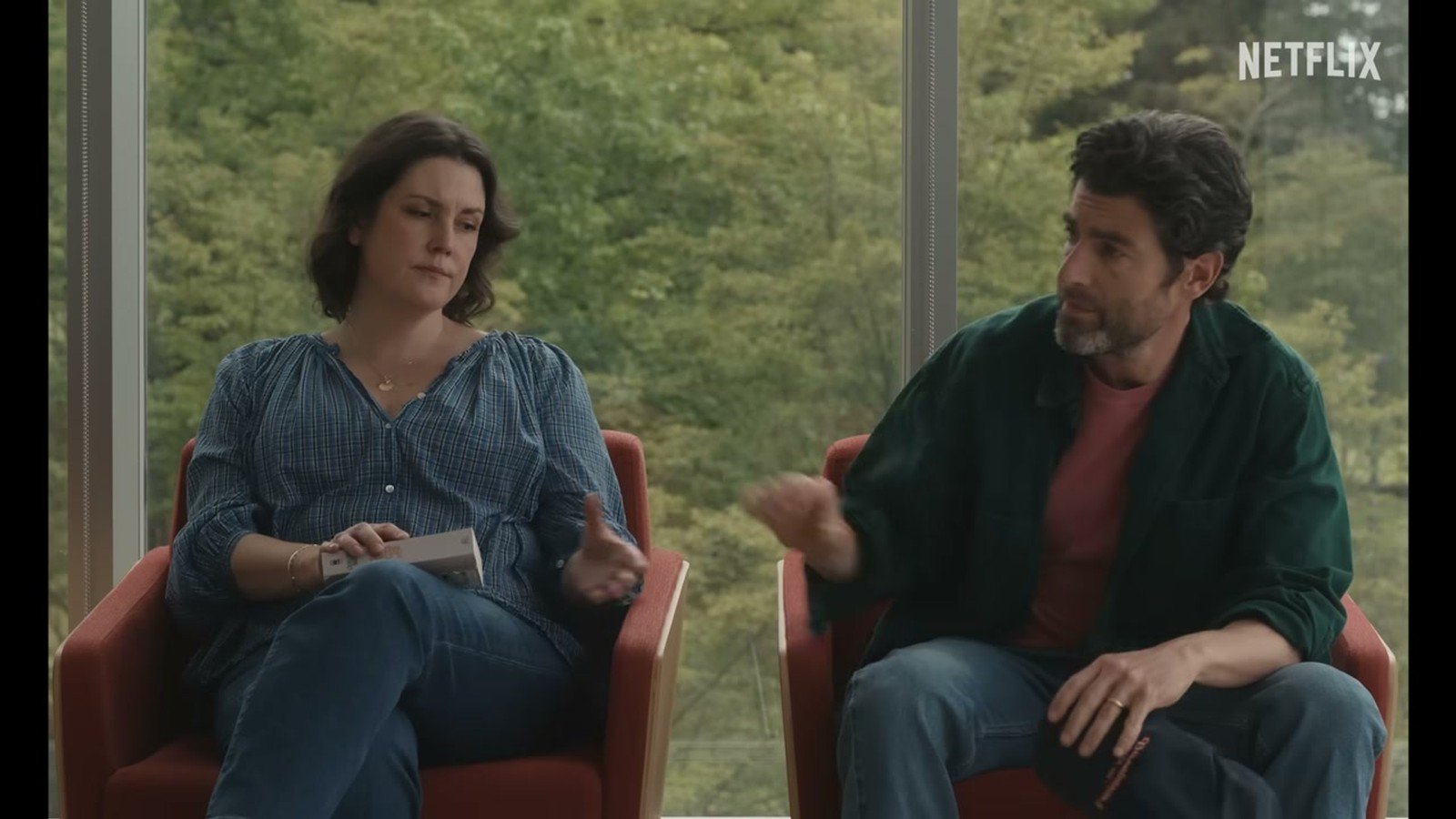 Melanie Lynskey e Max Greenfield sentados lado a lado em cena do filme