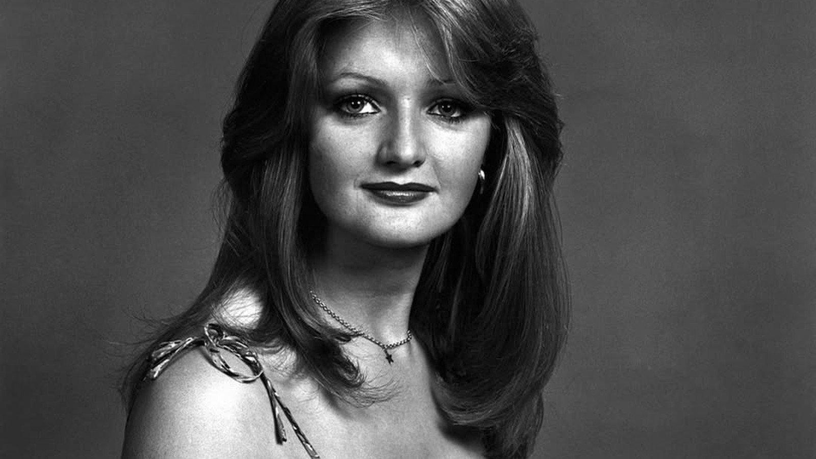 Retrato em preto e branco de Bonnie Tyler jovem, de blusa com ombros a mostra