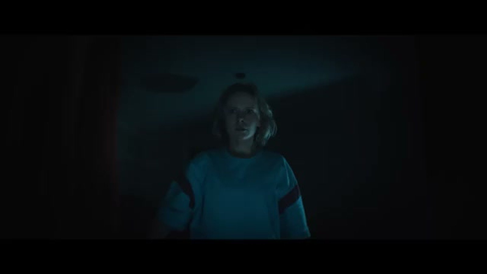 Cena escura de Sobrenatural Agora Entre Nos, com uma personagem iluminada por luz azulada