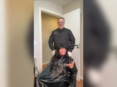 Gretchen sentada em cadeira de procedimento, com o médico em pé atrás dela