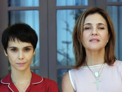 Débora Falabella, como Nina, e Adriana Esteves, como Carminha, lado a lado diante de uma janela em cena de Avenida Brasil