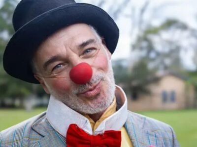 Carlos Cesare caracterizado como o Palhaco Eugenio Garnize, de nariz vermelho, chapeu coco e gravata borboleta, num parque