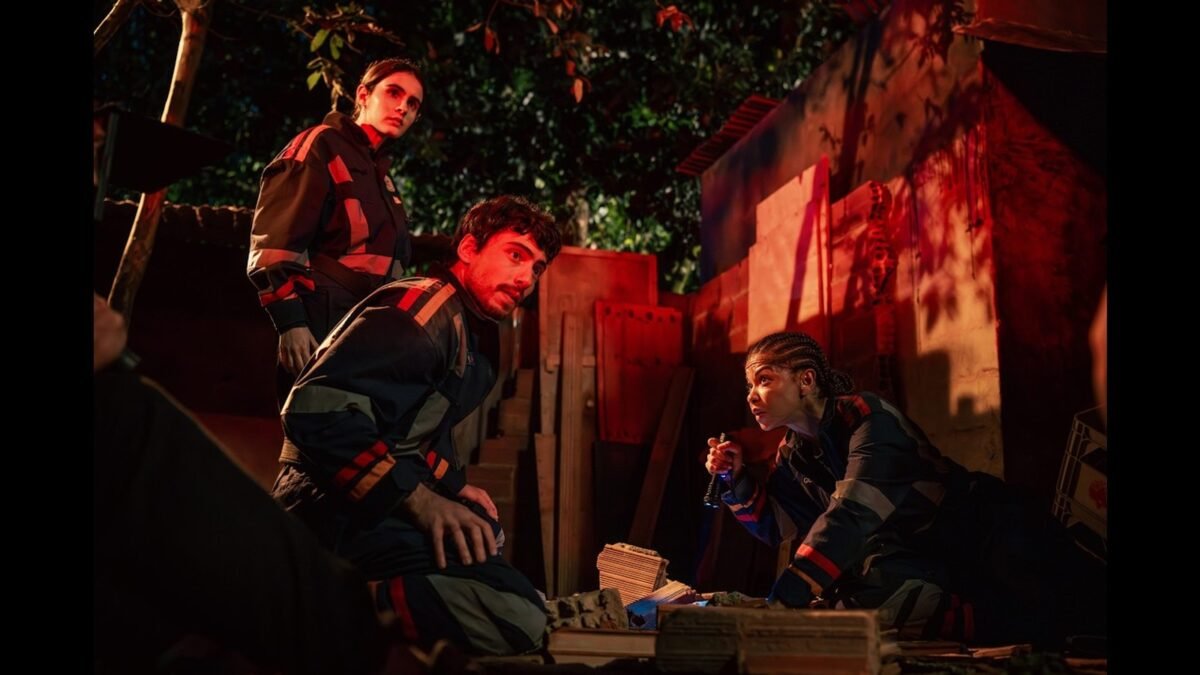 Tres socorristas de uniforme do SMU agachados num resgate noturno, em cena da serie Emergencia 53