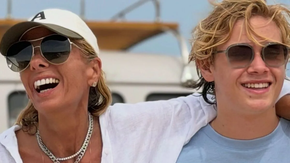 Adriane Galisteu e o filho Vittorio rindo num barco, os dois de óculos escuros