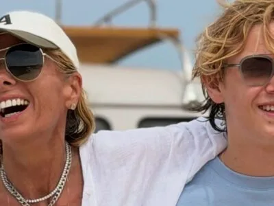 Adriane Galisteu e o filho Vittorio rindo num barco, os dois de óculos escuros