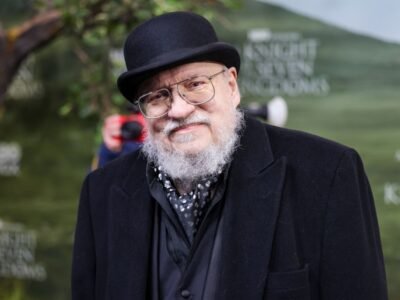 George R.R. Martin de boina e casaco preto em evento ao ar livre
