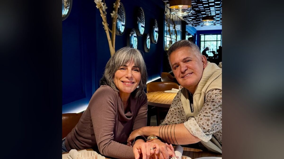 Glória Pires e Orlando Morais de mãos dadas e sorrindo, sentados à mesa de um restaurante