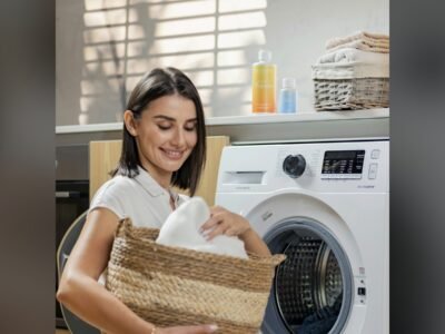 Mulher segurando um cesto de roupa suja em frente à máquina de lavar, em casa