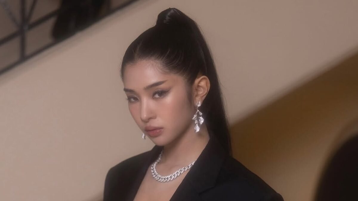 Sophia Laforteza de blazer preto e colar de prata, cabelo preso, olhando para a câmera