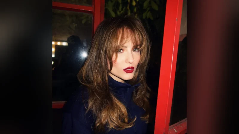 Larissa Manoela, de cabelo solto com franja e batom vermelho, olha para a câmera à noite