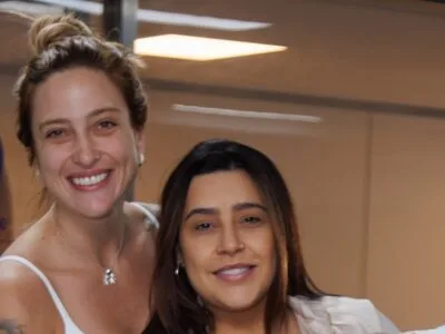 Lauana Prado e Tati Dias sorrindo na saída da maternidade, com o logo do Pro Matre ao fundo