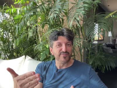 Lito Sousa de camiseta azul, olhando para a camera, em video gravado em casa