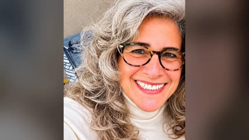 Lúcia Veríssimo, de cabelo grisalho e óculos de armação tartaruga, sorri de gola alta branca