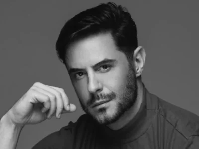 Retrato em preto e branco de Ricardo Tozzi, de barba curta, apoiando o rosto na mão