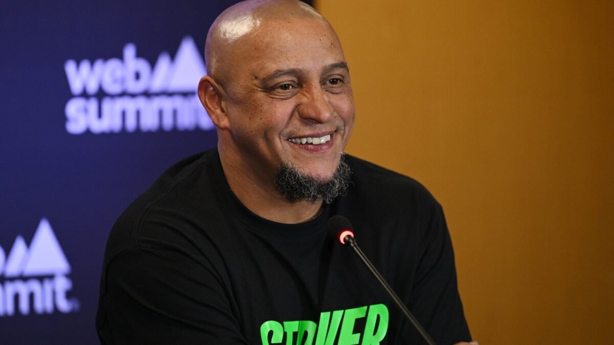 Roberto Carlos de camiseta preta, sorrindo, durante painel do Web Summit em 2023