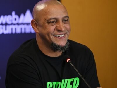 Roberto Carlos de camiseta preta, sorrindo, durante painel do Web Summit em 2023