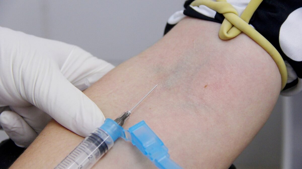 Punção venosa: agulha aplicada no braço de uma paciente por profissional de saúde com luvas