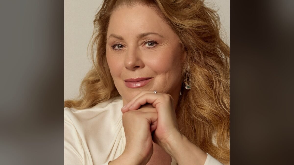 Vera Fischer em retrato de blusa branca, com as mãos sob o queixo, olhando para a câmera