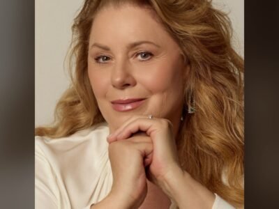 Vera Fischer em retrato de blusa branca, com as mãos sob o queixo, olhando para a câmera