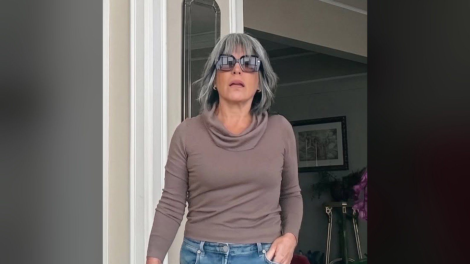 Glória Pires de óculos escuros, blusa marrom e jeans, caminhando