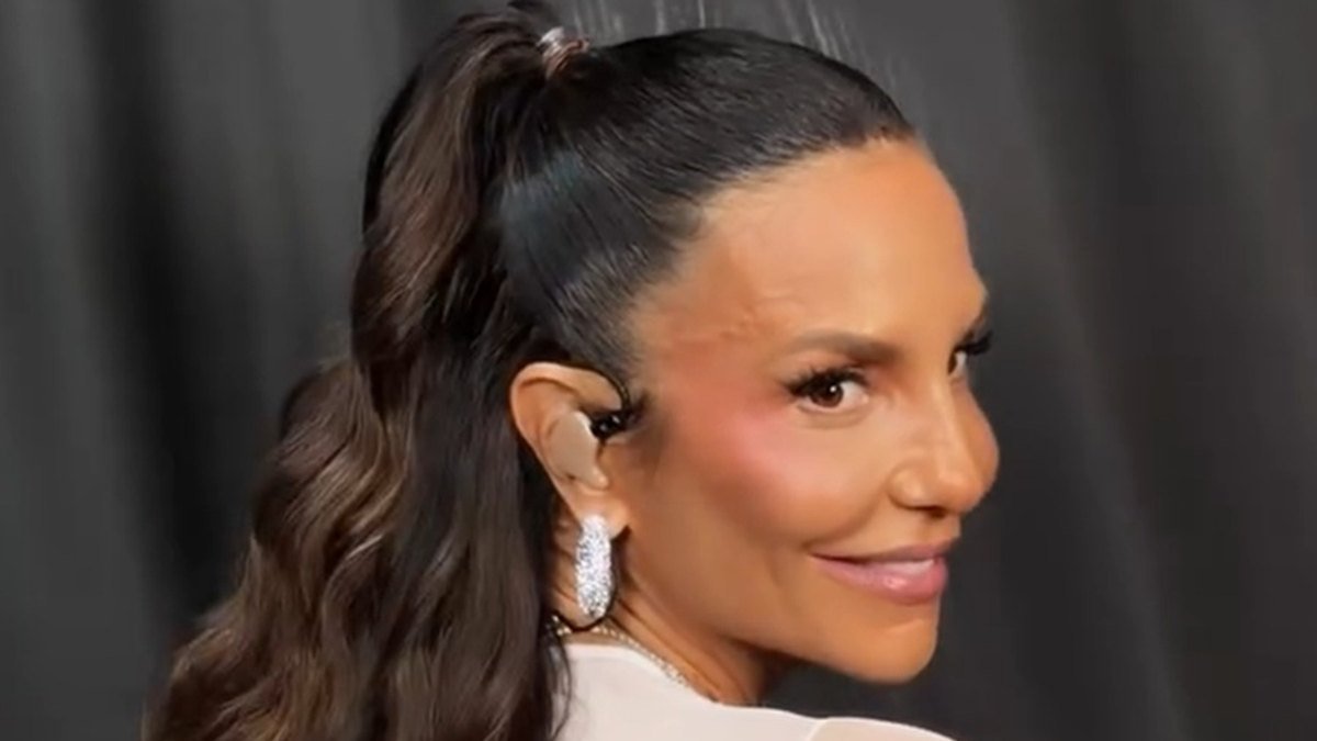 Ivete Sangalo de rabo de cavalo alto e brinco de pedra, sorrindo em evento.