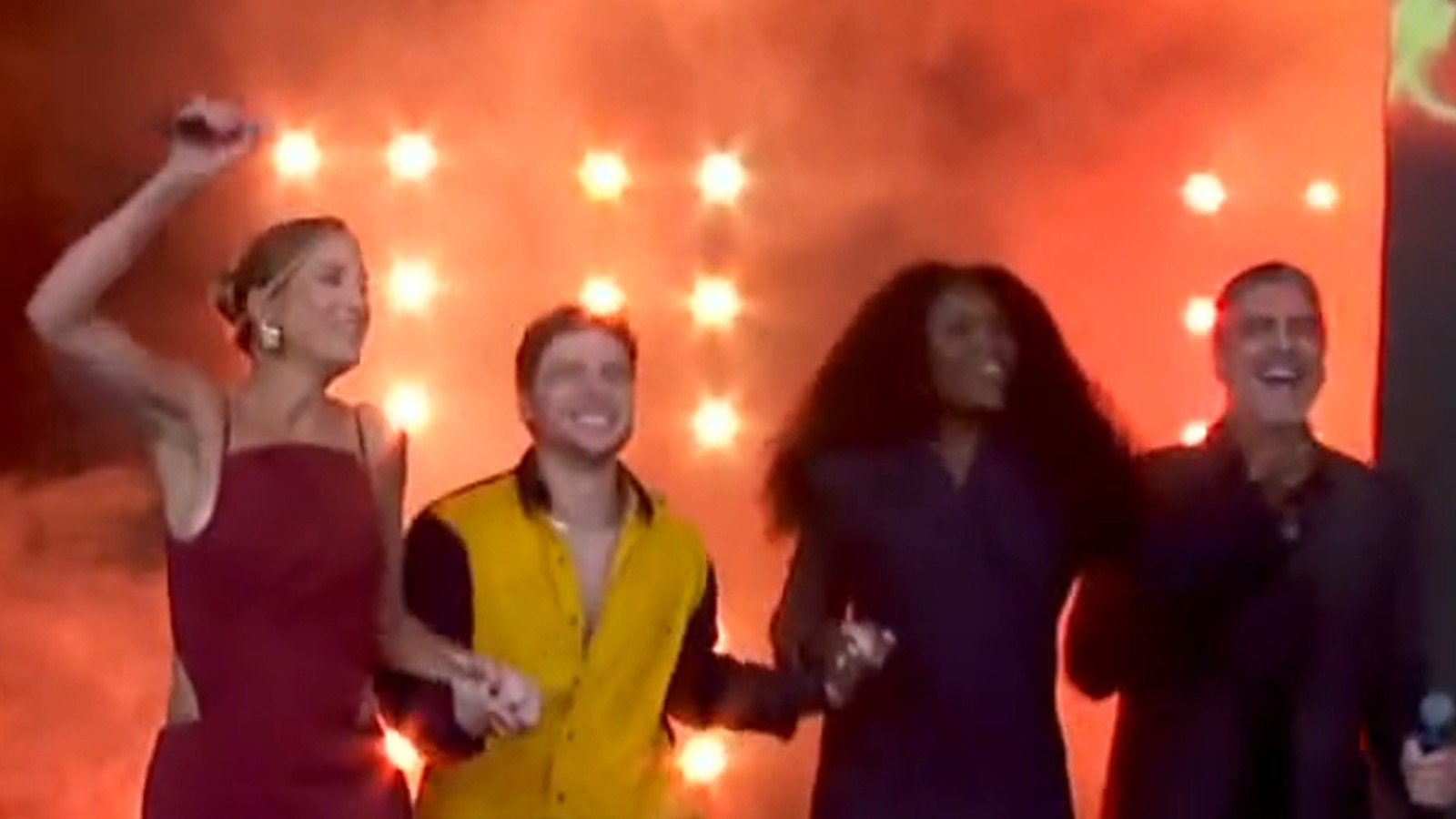 Participantes do Danca dos Famosos dancam lado a lado no palco iluminado de vermelho