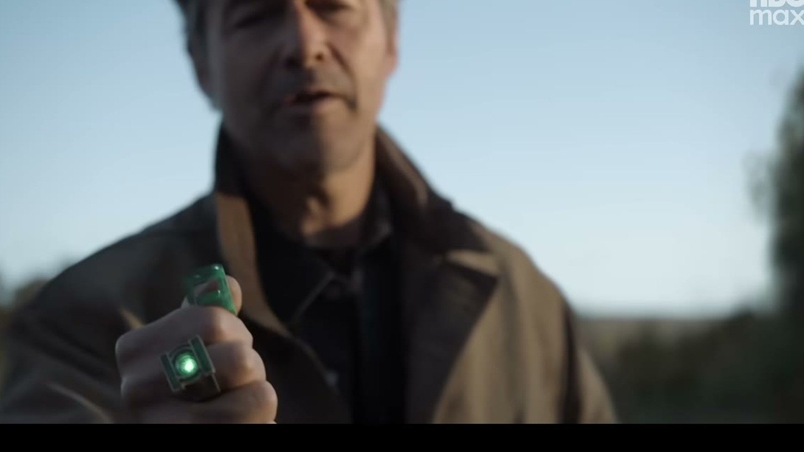 Kyle Chandler como Hal Jordan segura diante do rosto o anel verde dos Lanternas