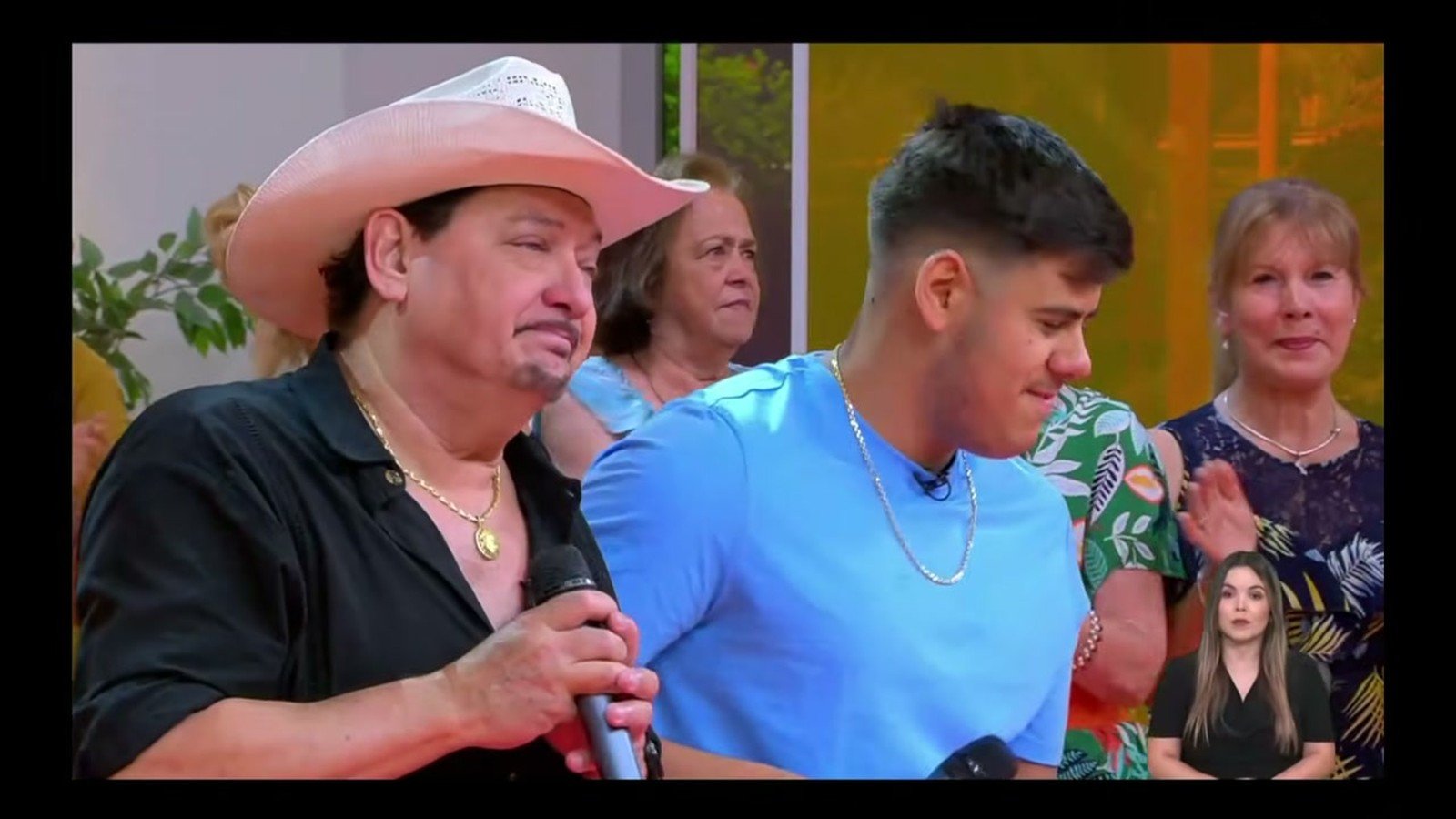 Lucas de chapeu branco ao lado do sobrinho Matheus Junior, de camisa azul, num palco de televisao