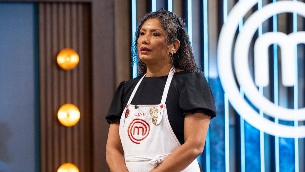 Participantes do MasterChef com os braços erguidos na bancada.