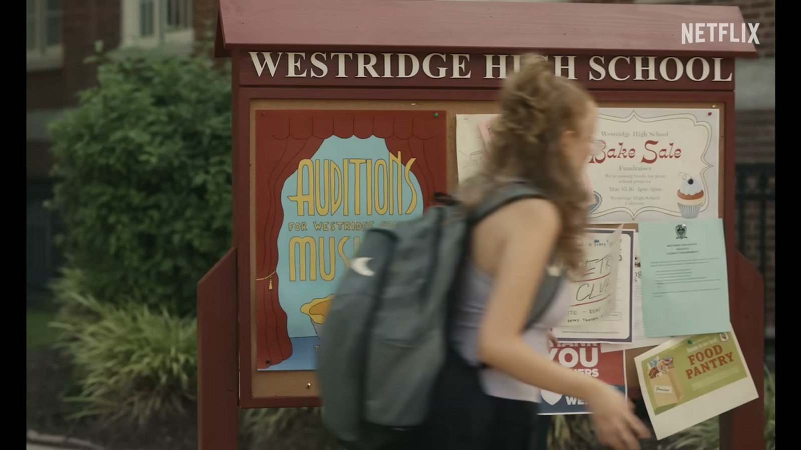 Sophie caminha com mochila diante do mural da Westridge High School