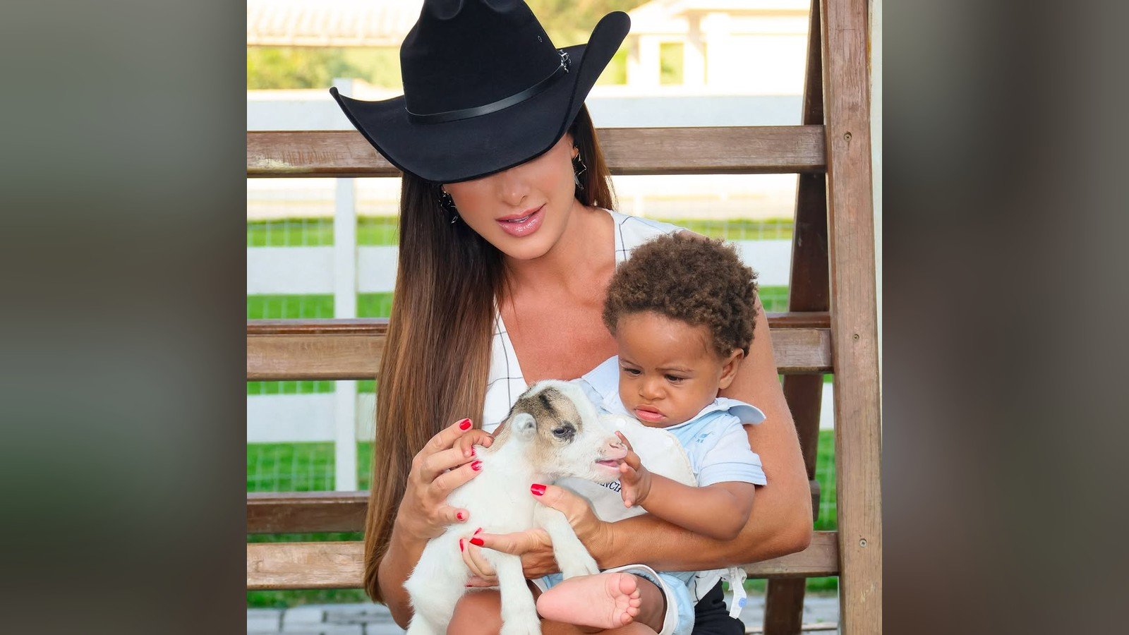 Nicole Bahls de chapeu preto segura um cabrito filhote ao lado de um bebe