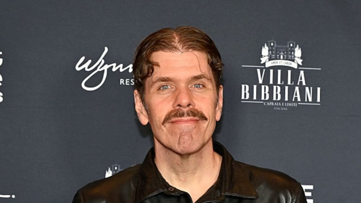 Perez Hilton de jaqueta de couro preta em painel de evento.