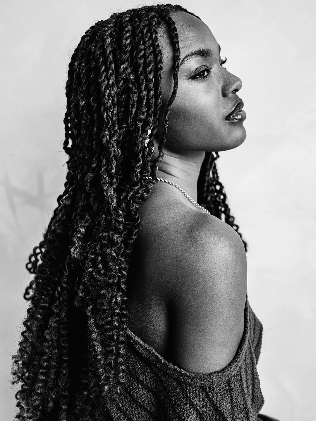 Retrato de perfil de Maya Boyd em preto e branco, com tranças longas